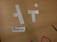 Schülerlösung von Anouar: 3 ausgeschnittene Formen: 5 Quadrate senkrecht untereinander, mittig ein Quadrat an der linken Seite. Ein einzelnes Quadrat. 5 Quadrate in T-förmiger Anordnung.