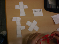 Schülerlösung von Kürsat: 3 ausgeschnittene Formen:  6 Quadrate in kreuzförmiger Anordnung. 5 Quadrate in Form des Pluszeichens. 5 Quadrate senkrecht untereinander, ganz oben ein Quadrat an der linken Seite, ein Quadrat mittig an der rechten Seite.